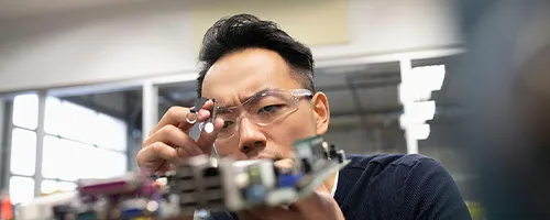 An asian scientist working on a computer motherboard